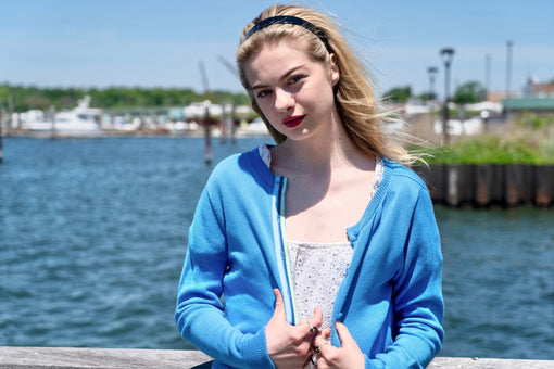 Woman wearing a cotton ribbon cardigan draped over her shoulders with a white skirt and striped Breton top on a summer day