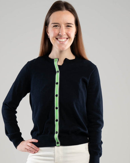 woman wearing navy ribbon cardigan with green, white and navy striped ribbon trim on plain background