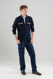 Man wearing Noyac Knits Finn knit overshirt in navy premium soft lightweight merino wool with signature ribbon detailing on pockets styled  over light blue t-shirt with jeans and oafers on plain background.