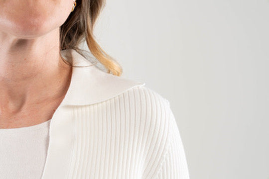 Close-up of a person wearing a white robbed sweater with collar with a blurred background