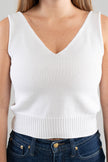 Close up of woman wearing a Noyac Knits white double v-neck sleeveless crop top in breathable cotton and blue jeans against a white  background
