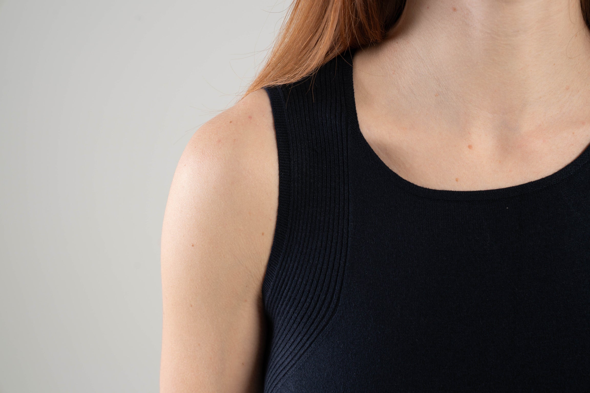 Close up of neckline and traveling rib pattern on Noyac Knits navy scoop neck tank in soft and lightweight ecoviscose on plain background
