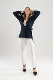 Woman wearing Noyac Knits navy wrap ribbed sweater over red and white striped square neck top styled with white pants and navy espadrilles against a plain background