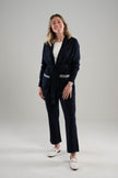 Woman wearing a Noyac Knits long belted navy cardigan with navy and white ribbon-trimmed pockets over white featherweight scoop neck sleeveless sweater and navy knit ankle length pants -- all in environmentally sustainable ecoviscose on a white background