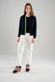 Woman wearing Noyac Knits navy Julie ribbon cardigan trimmed with with green, navy and white striped ribbon over a navy crew neck sleeveless sweater, both in premium Egyptian cotton, styled with white jeans and navy espadrilles  on a white background