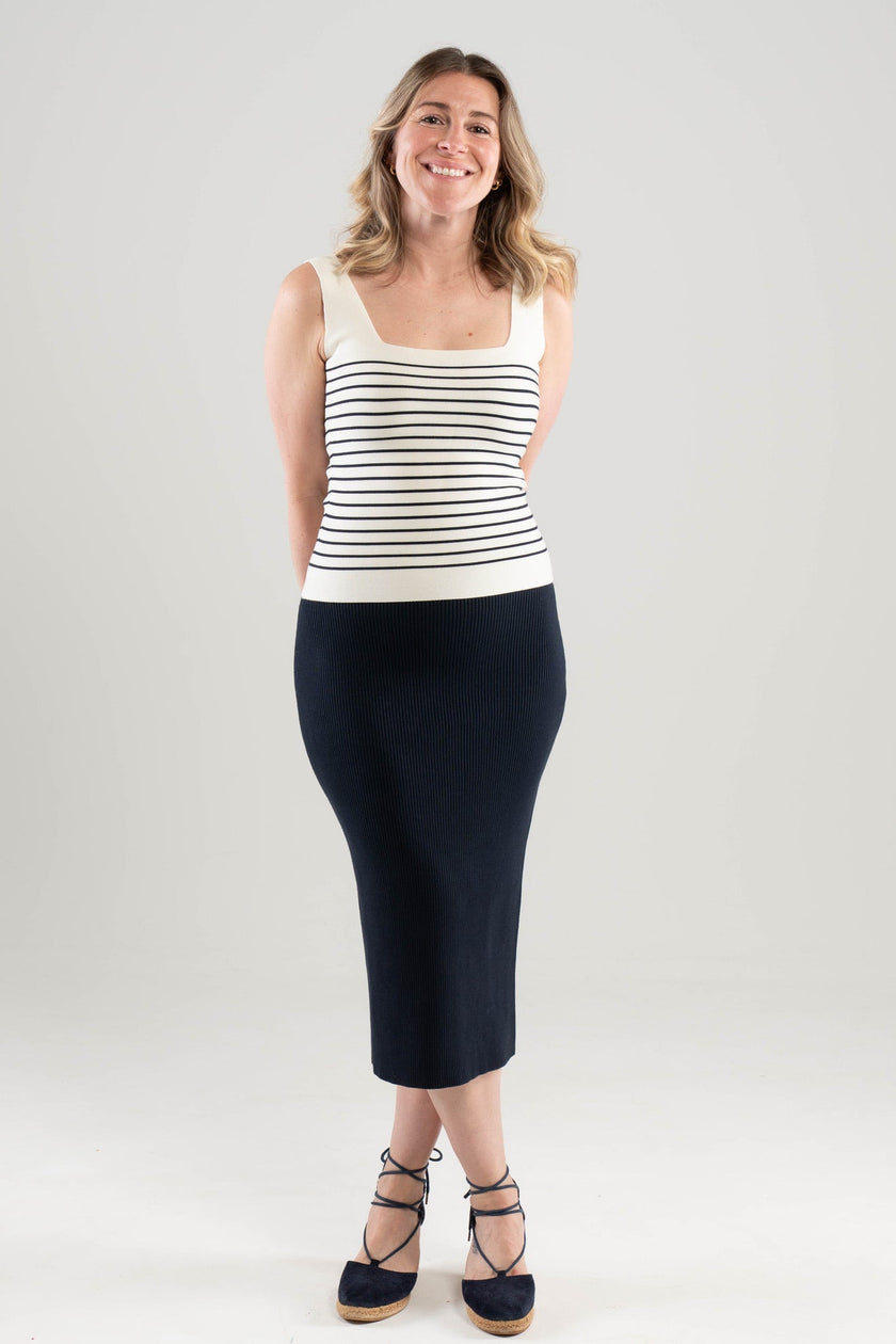 Woman wearing Noyac Knits Breton stripe square neck tank in white with navy stripes over navy midi skirt - both in machine washable ecoviscose - on a plain background