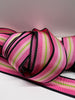 Close up of grosgrain ribbon with black, hot pink, light pink, and lime green stripes on plain background.