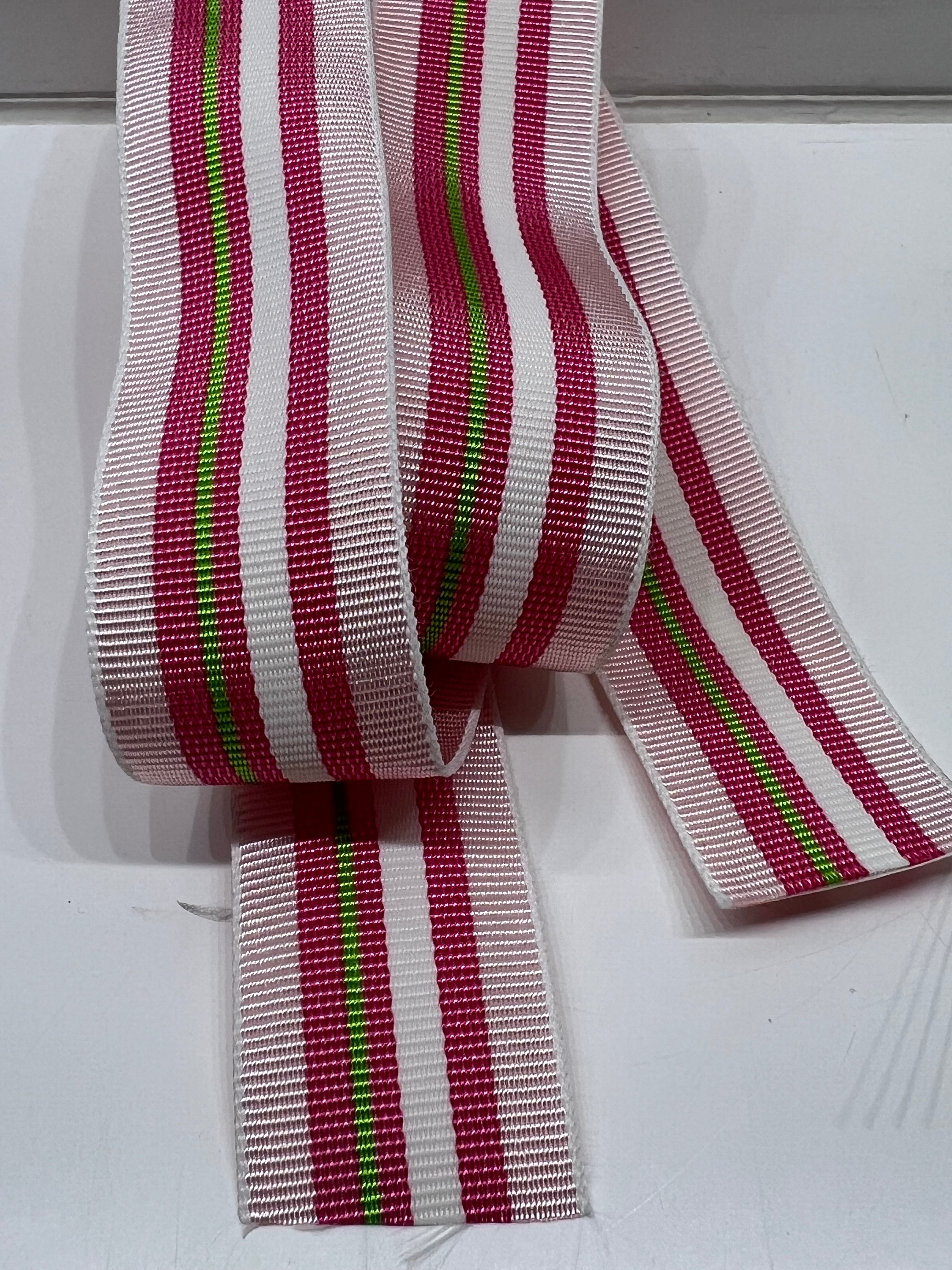 Close up of grosgrain ribbon with light pink, dark pink, white, and lime green stripes on plain background.
