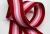 close up of grosgrain ribbon with red, pink and white stripes on plain backgound