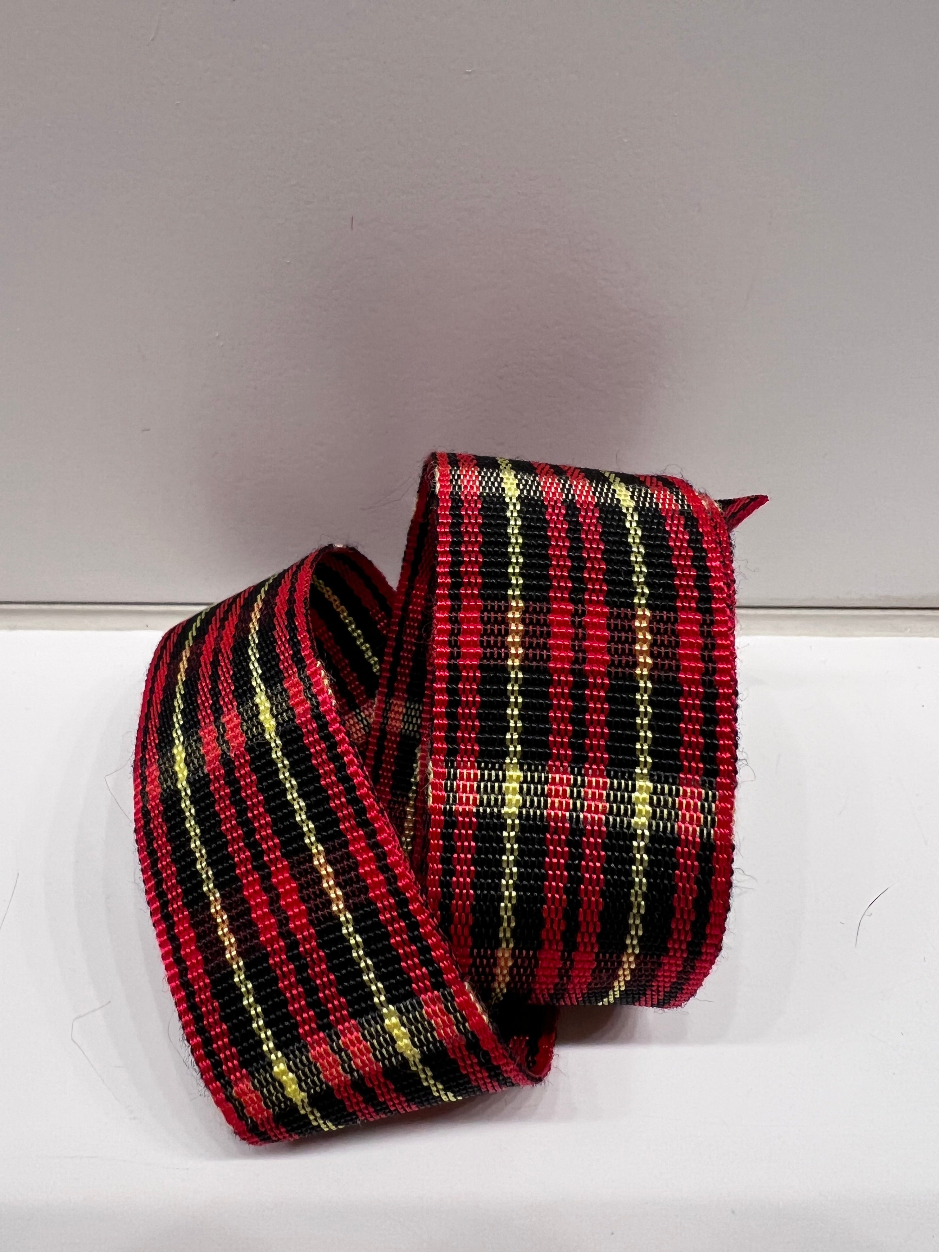 Close-up of red, black and gold tartan plaid grosgrain ribbon on plain background.