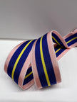 Close up of grosgrain ribbon with pink, cobalt blue and yellow stripes on plain background.