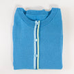 Folded Noyac Knitws French blue ribbon cardigan with a ribbon striped in blues and greens and light blue buttons made in breathable premium cotton on a light gray background