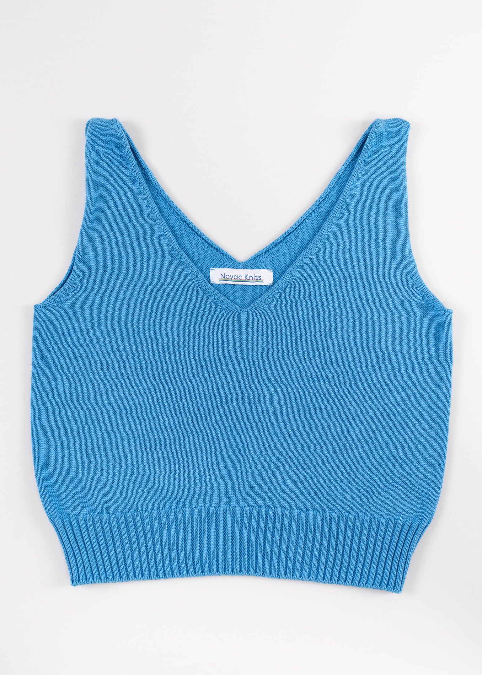 Lay flat photo of Noyac Knits light blue double v-neck crop tank made in lightweight, soft cotton on white background
