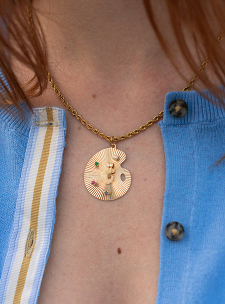Close up of woman wearing french blue cardigan with striped ribbon trim in blue, white and tan stripes and wearing gold necklace