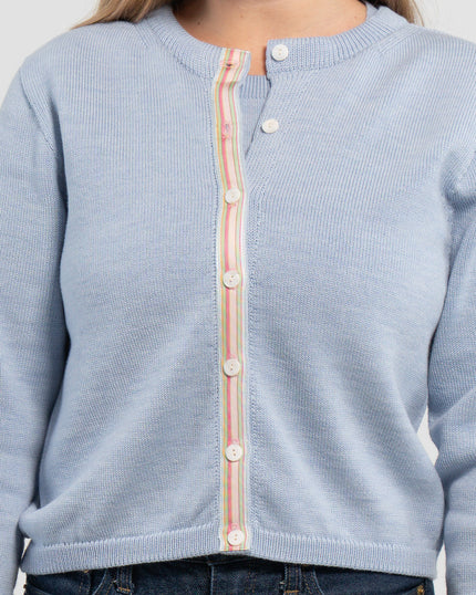 Close up of baby blue crop cardigan with white mother of pearl buttons and pastel pink, green and blue striped grosgrain ribbon trim and jeans on plain background.