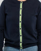 Close up of buttoned navy cardigan with navy pearlized buttons and navy, green and white striped grosgrain ribbon trim.