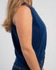 Close up side view of woman wearing cobalt blue crop sleeveless sweater and jeans on plain background.