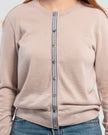 Close up of woman wearing beige cardigan with iridescent shell buttons and purple, lavender, teal and tan striped grosgrain ribbon trim and jeans.