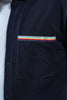 Close up of navy overshirt pocket with ribbon trim with stripes in navy, red, yellow, white, and green.