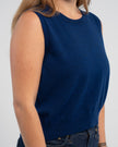 Closeup of woman wearing Noyac Knits cobalt blue crew neck sleeveless sweater in premium merino wool styled with  jeans on plain background.