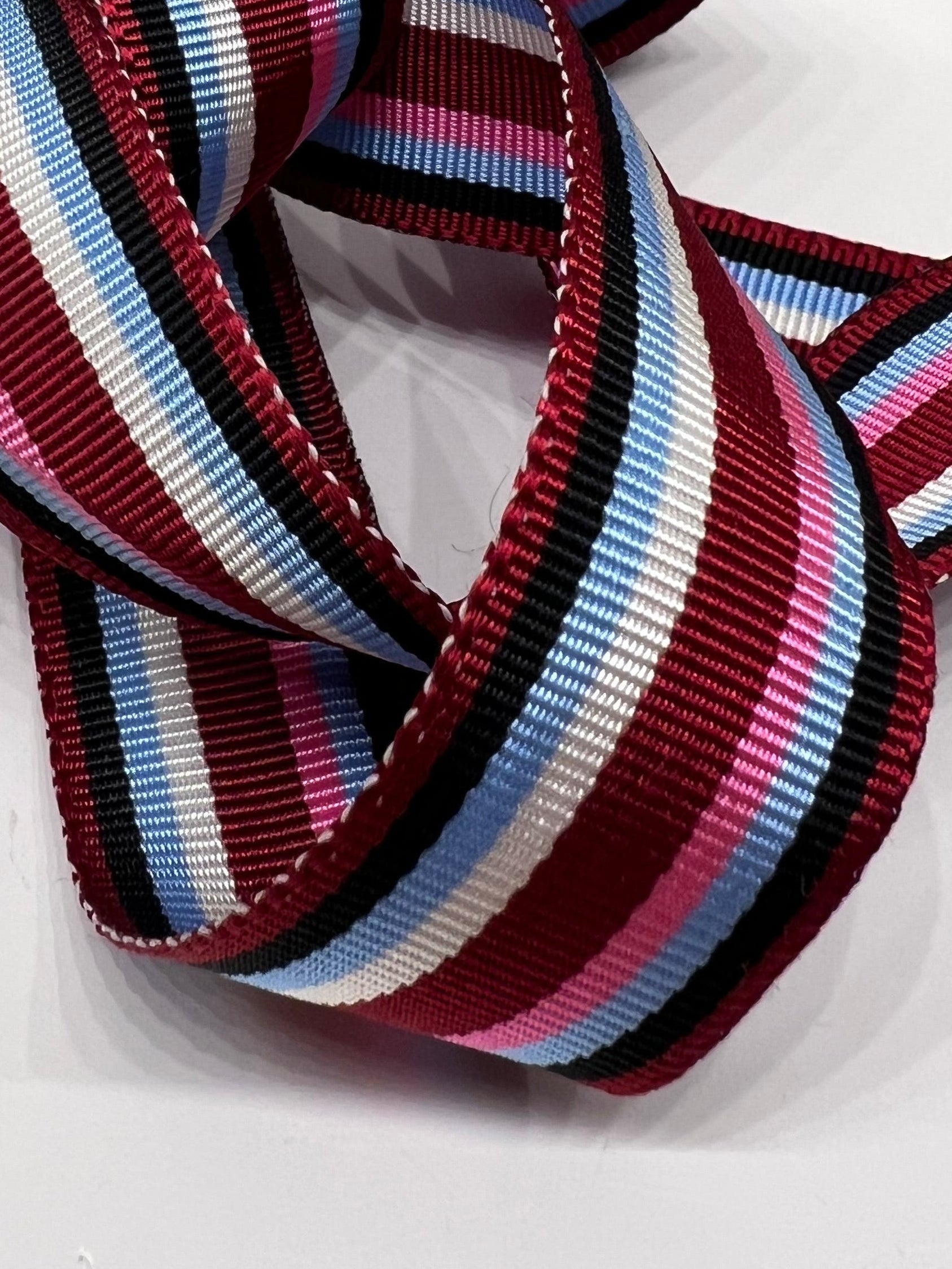 Close  ribbon in stripes in burgundy, navy, light blue, pink and white.