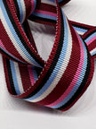 Close  ribbon in stripes in burgundy, navy, light blue, pink and white.