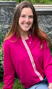 Woman wearing Noyac Knits Grace classic cardigan in beautiful raspberry pink with signature ribbon trim and pink buttons -- knit in lightweight premium merino -- styled with jeans in outdoor setting with greenery and stone wall in background