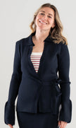 Woman wearing a Noyac Knits navy ribbed wrap sweater over a red and white striped square neck top on a white background