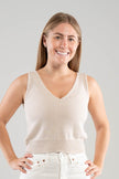 Woman wearing a Noyac Knits light sand colored cotton double v-neck crop tank top styled with white jeans  on a white  background