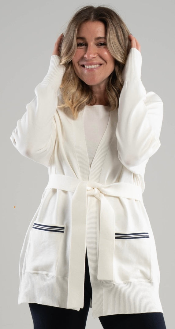 Woman wearing a white Noyac Knits long belted cardigan with navy and white striped ribbon trimmed pockets in cozy soft ecoviscose  on a white background