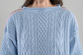 Close-up Noyac Knits Channing boatneck pullover in beautiful baby blue featuring cabling and signature ribbon trim on shoulder, knit in premium soft merino wool  on plain background.