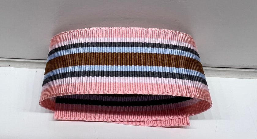 Striped ribbon with pink, blue, navy, and brown colors on a white background