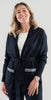 Woman wearing a Noyac Knits navy blue long belted cardigan with navy and white striped ribbon-trimmed pockets made in cozy soft ecoviscose on a plain background